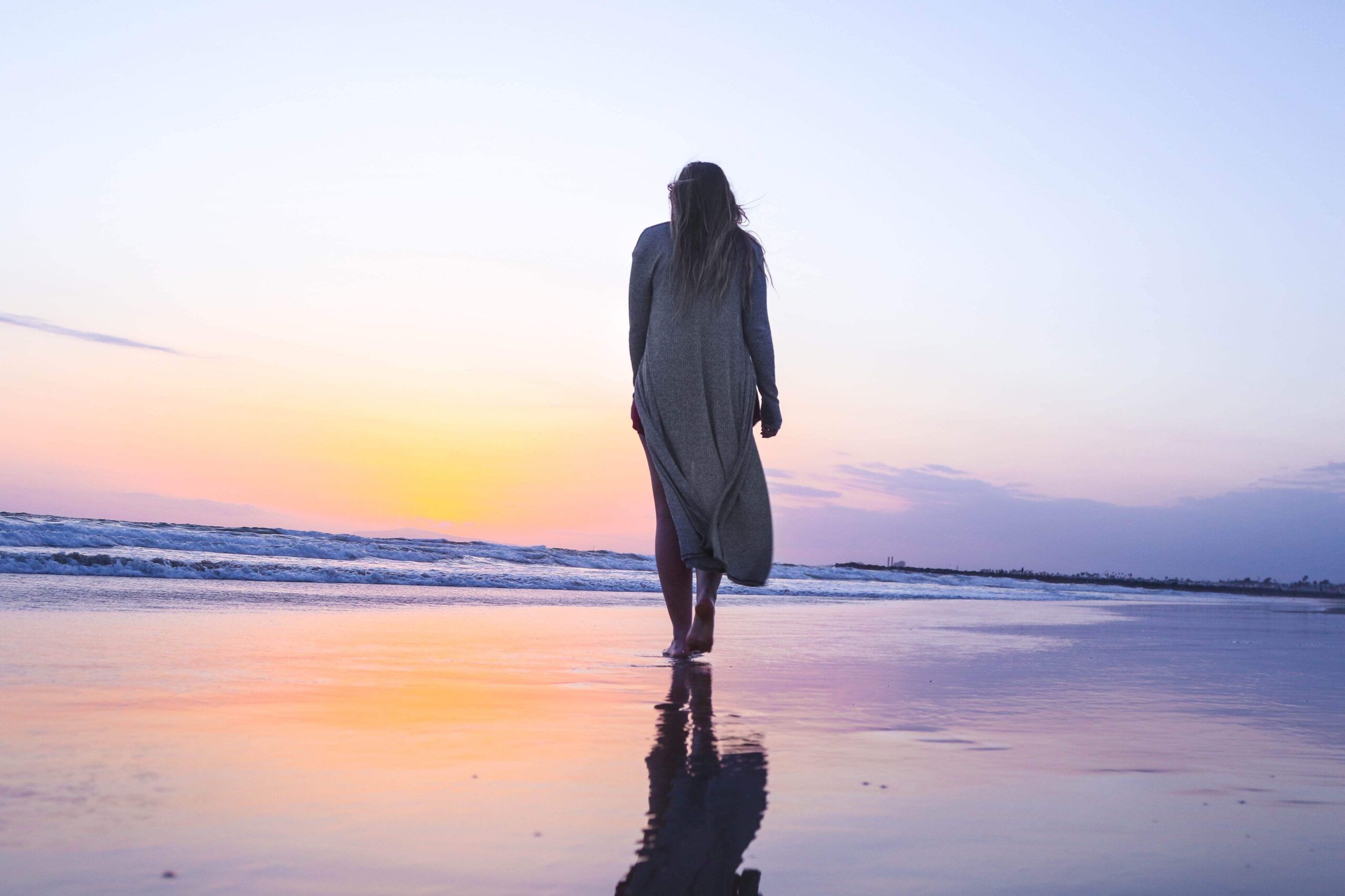 Woman walking on the beach at sunset