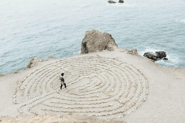 person walking through stone maze near the ocean