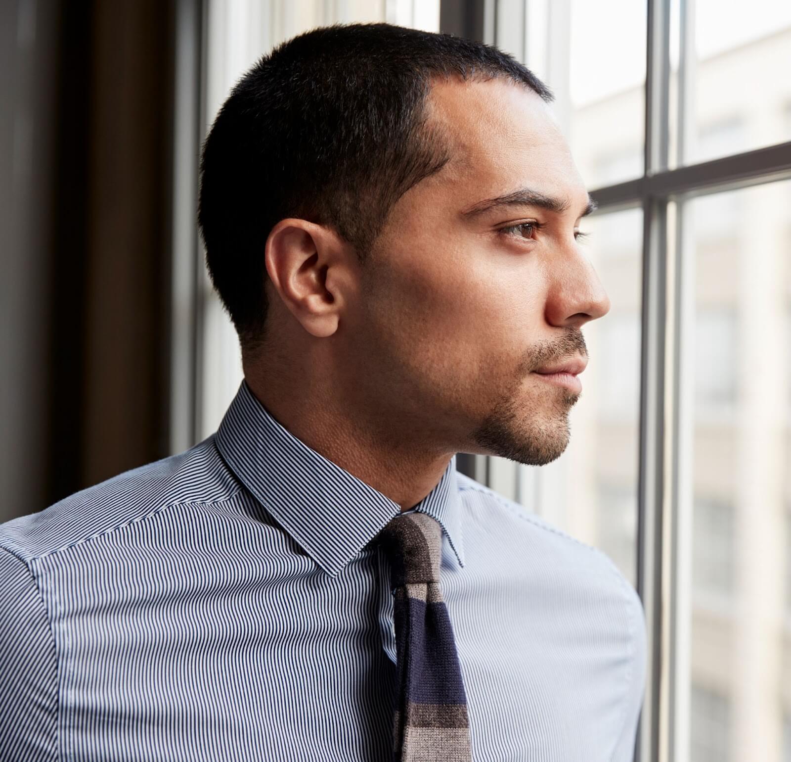 Young Hispanic Business man Looking out of Window