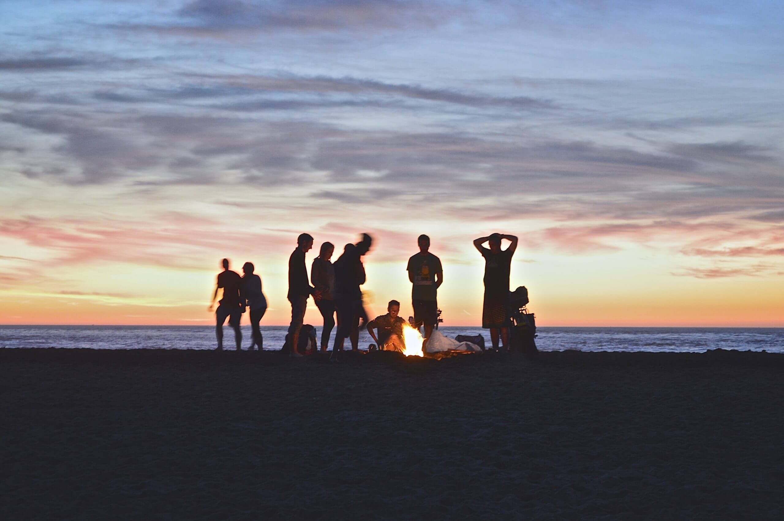 friends on a los angeles beach enjoying a bonfire together