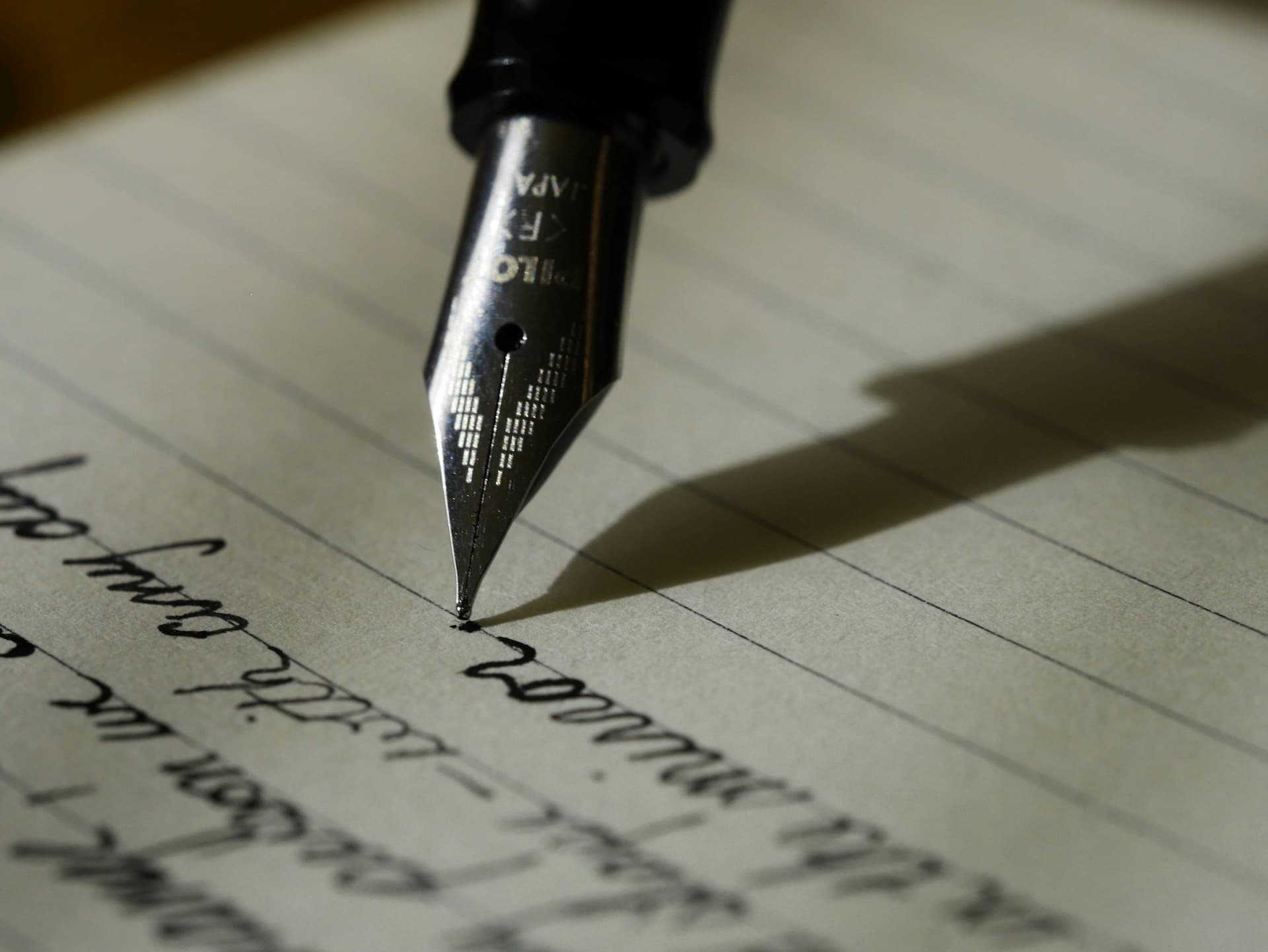 A close-up of a pen writing on lined paper, symbolizing the reflective practices and letter-writing exercises used in grief recovery and attachment-based therapy.