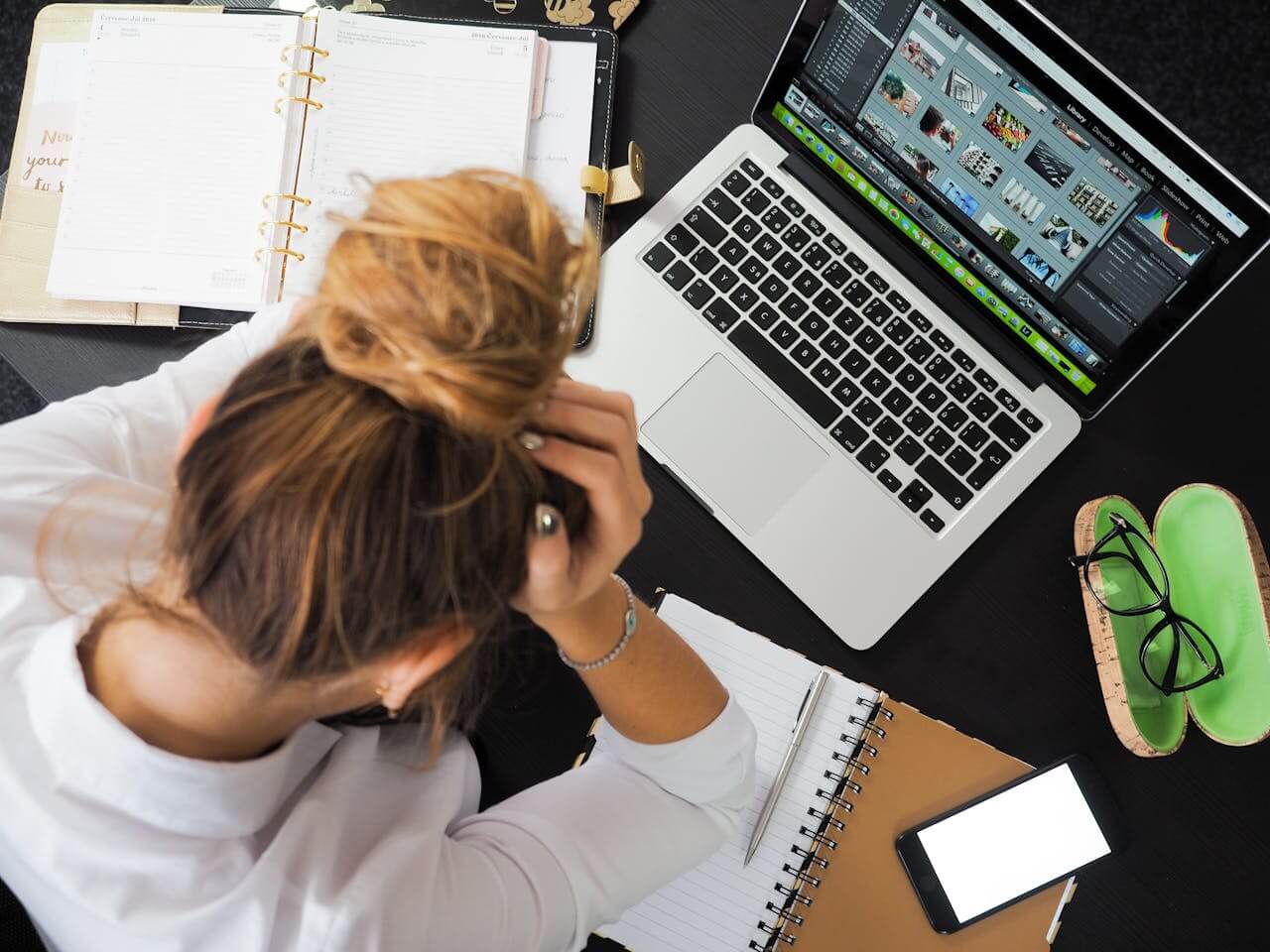 Overwhelmed woman with her head in her hands at a desk, symbolizing burnout and stress, featured in a post by a Los Angeles and Encino therapist.