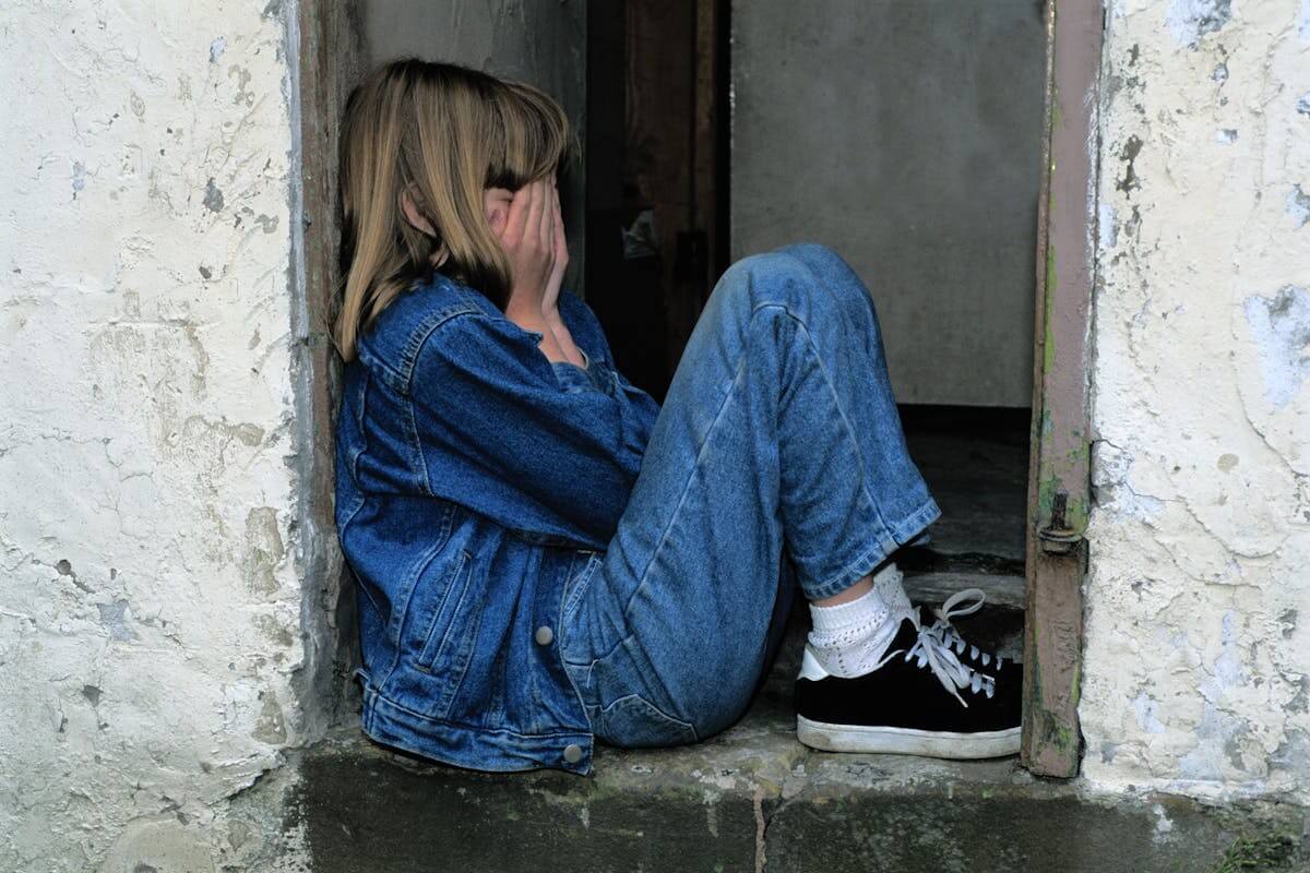 A child sitting alone with their face in their hands, representing the impact of childhood betrayal trauma—supported through therapy in Los Angeles and Encino