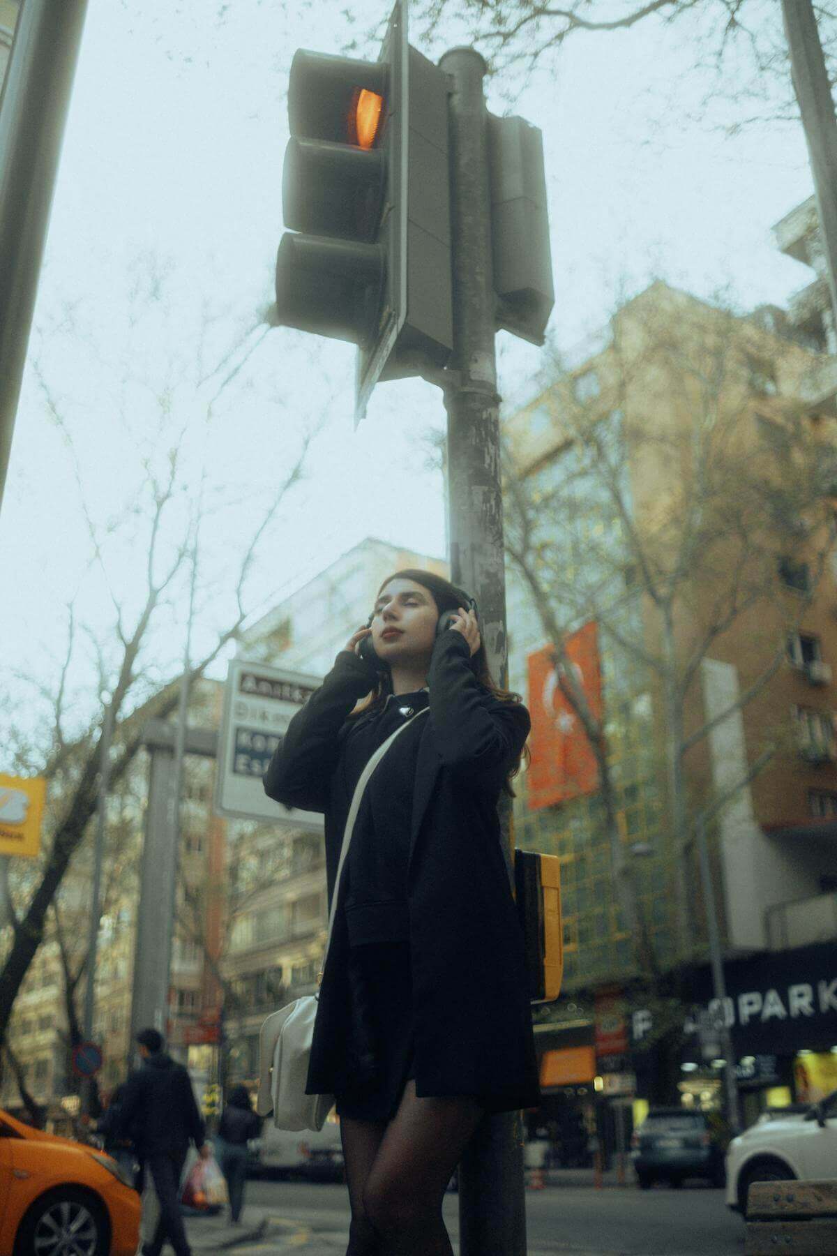 Woman standing at a crosswalk under a yellow traffic light, symbolizing red flags and hesitation in relationships—used in blog by Encino therapist Kirstin Carl, LMFT, offering attachment-based therapy in Los Angeles and online throughout California.