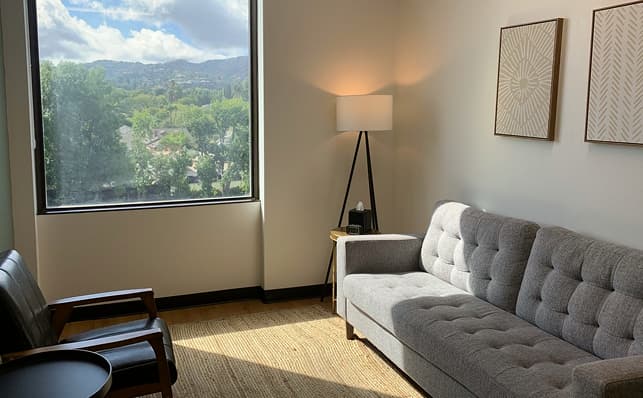 A comfortable couch placed by a window, offering a picturesque backdrop of distant mountains.