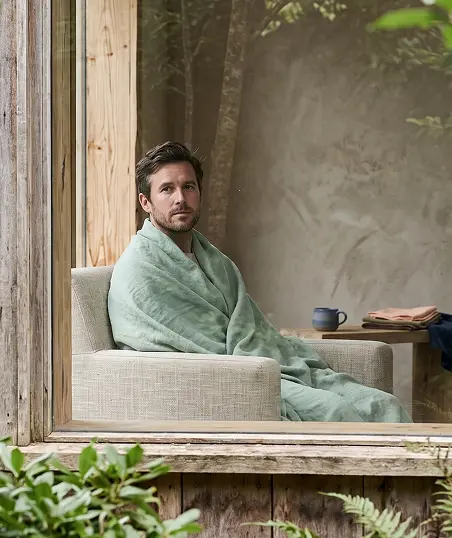 A man sits comfortably in a chair, draped in a towel, suggesting a moment of leisure.