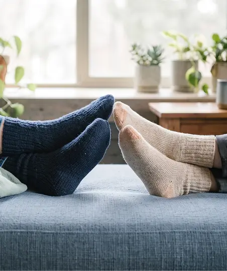 Two individuals relax on a couch with their feet propped up, enjoying a casual moment together.