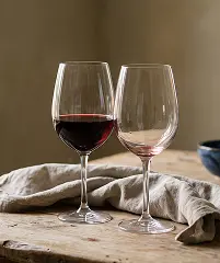 Two elegant wine glasses on a table beside a neatly folded napkin.