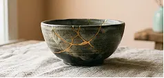 A black and gold bowl featuring a noticeable crack along its surface.