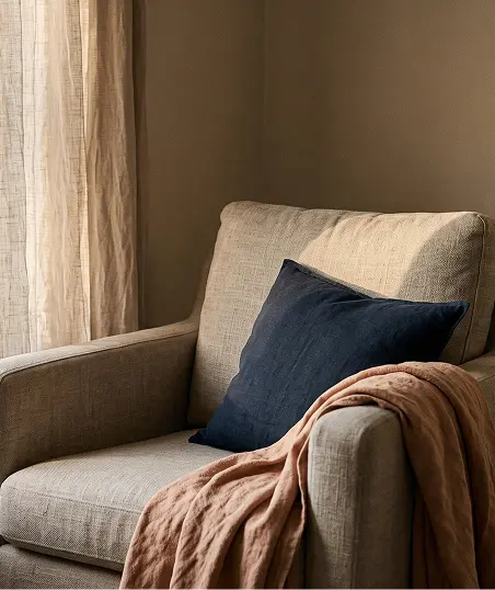 A comfortable chair featuring a warm blanket and plush pillows